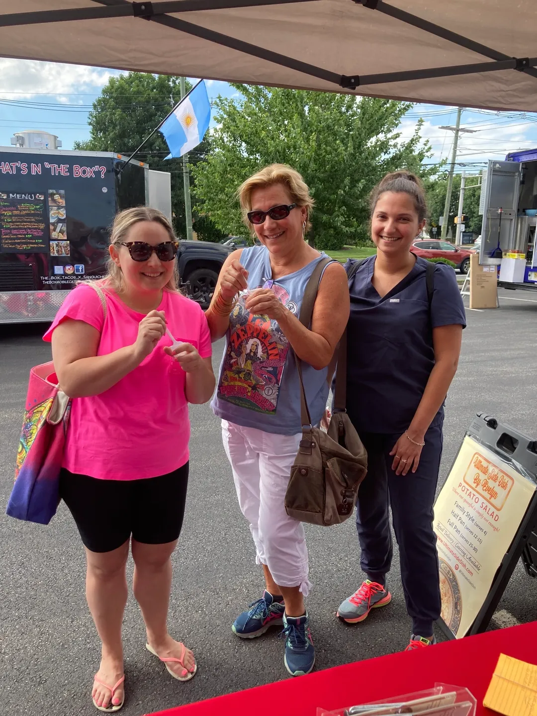 Three women standing next to each other in front of a food truck.